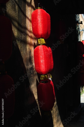 Vertical closeup of Chinese red festive lanterns on walls of a narrow street photo