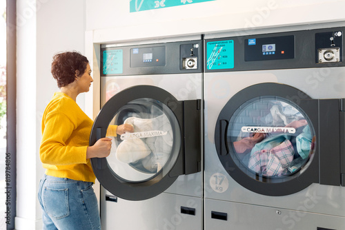 Young woman doing laundry at a public laundromat photo