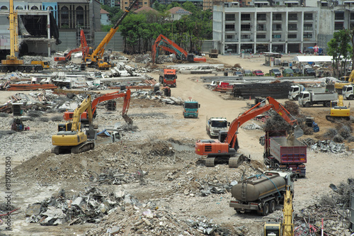 Many excavators working on the ground of the construction site while removing the salvage after the destruction of the building