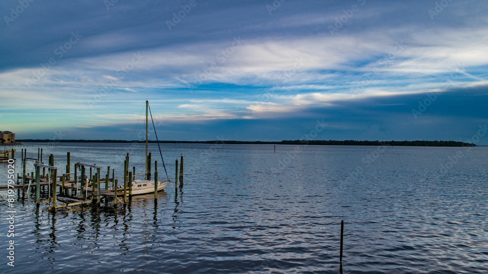 Scenic view of a marina featuring a wooden dock and sailboat tied to it