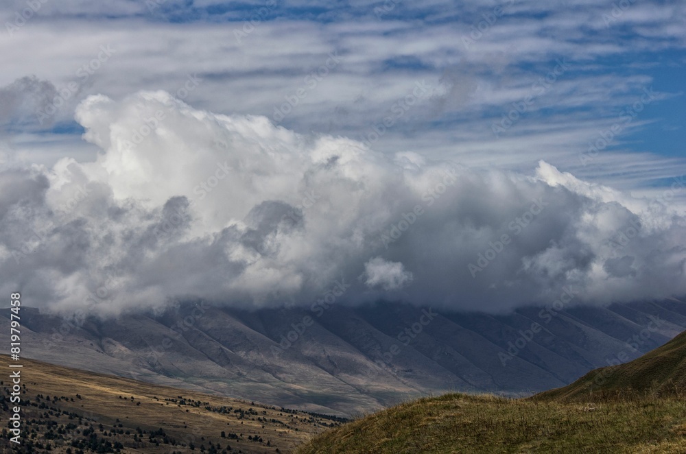 Scenic view of a mountainous landscape with rolling hills covered in clouds Scenic view of a mountainous landscape with rolling hills covered in clouds