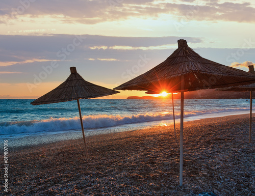 Summer sunset beach with strawy sunshades (Albania). photo