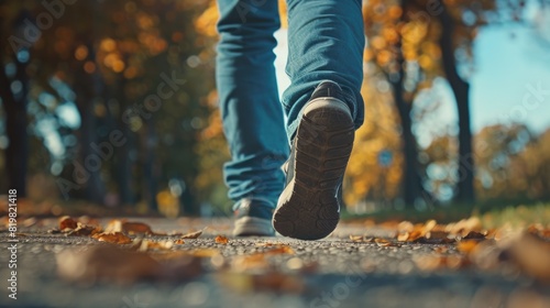A person walking on a path with leaves, suitable for autumn themes #819821418