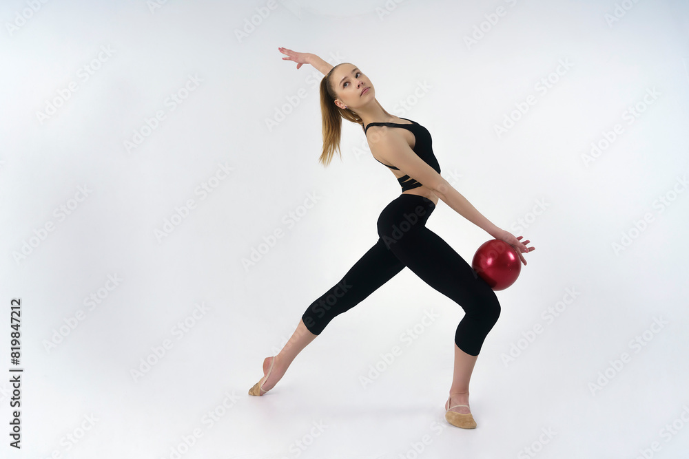 young gymnast in a photo studio shows the elements of exercises with a ball