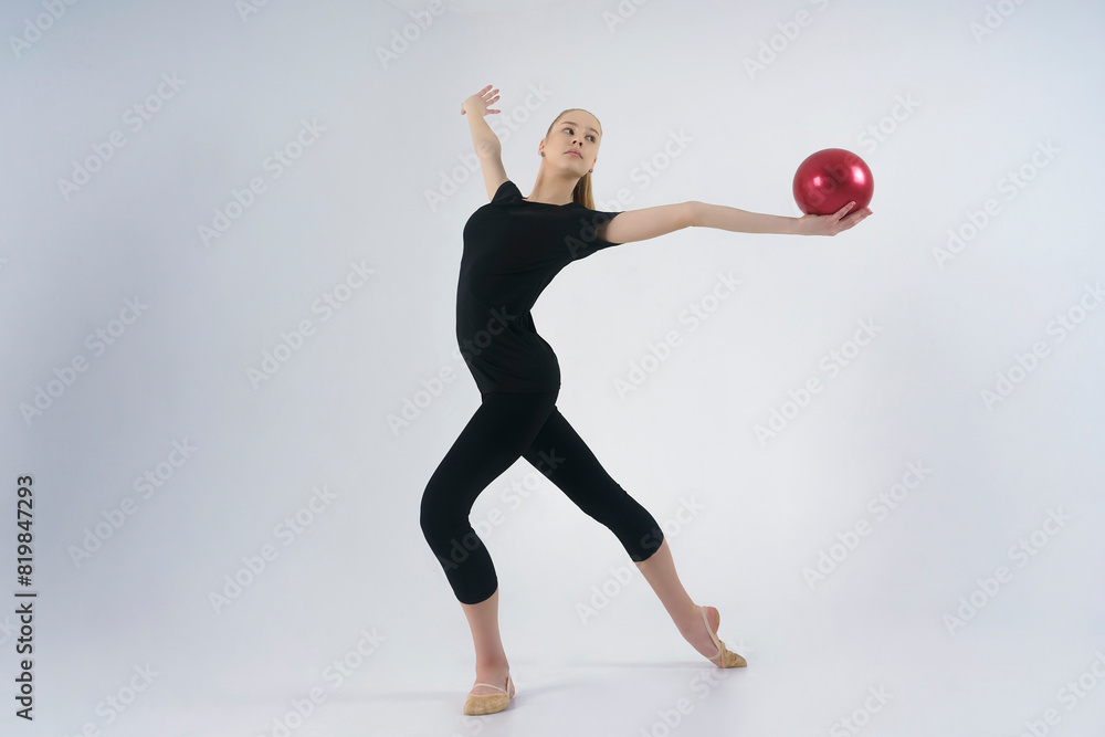 young gymnast in a photo studio shows the elements of exercises with a ball young gymnast in a photo studio shows the elements of exercises with a ball
