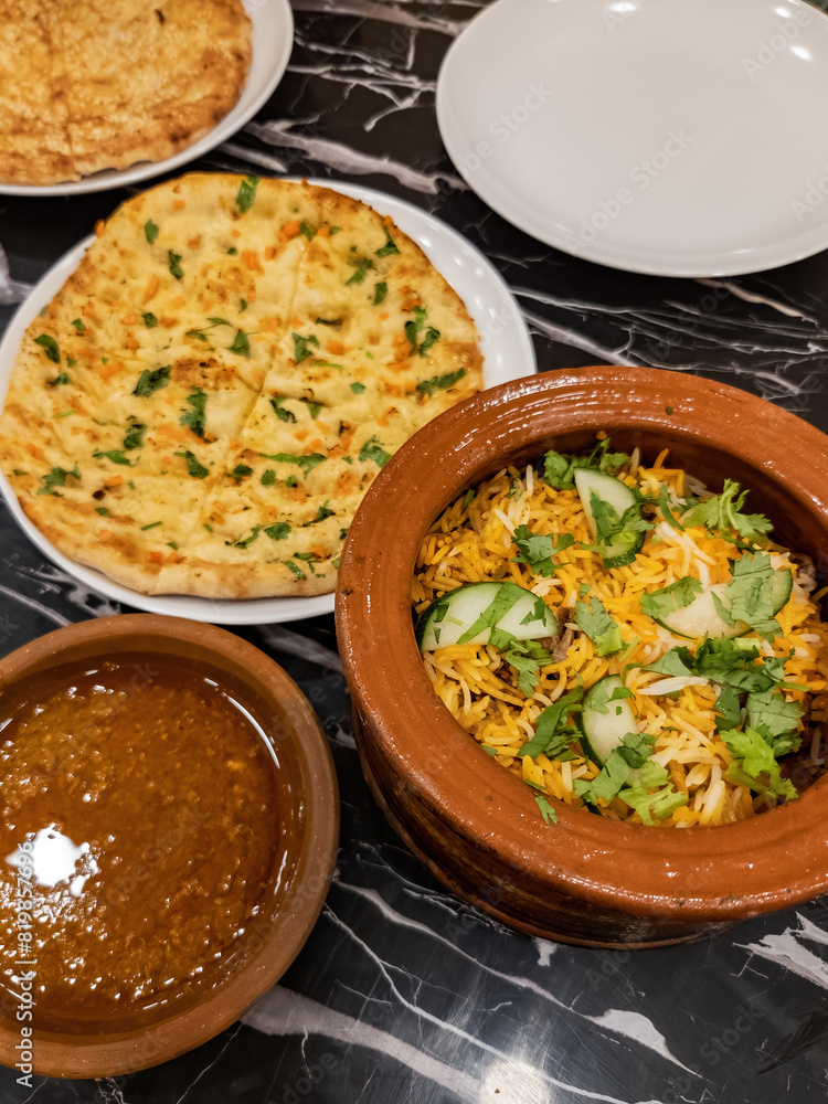 Rice from a claypot biryani is served with flatbread. Table-served Naan bread. Rice from a claypot biryani is served with flatbread. Table-served Naan bread.