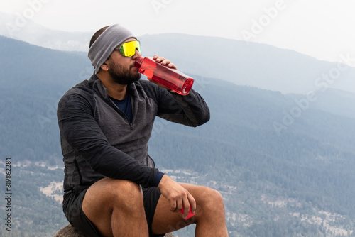 Hiker taking a break and hydrating on mountain trail photo
