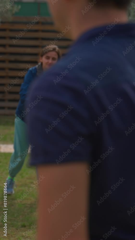 Woman catches green flying frisbee thrown by man against brown fence in countryside. Couple plays fun game in yard on cloudy day slow motion Vertical Shot. Woman catches green flying frisbee thrown by man against brown fence in countryside. Couple plays fun game in yard on cloudy day slow motion Vertical Shot.