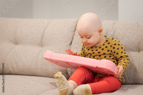 Baby girl with cancer and hair loss due to chemotherapy playing with a piano © bymandesigns