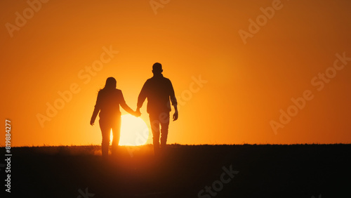 Silhouettes of a young couple walking side by side towards a picturesque sunset