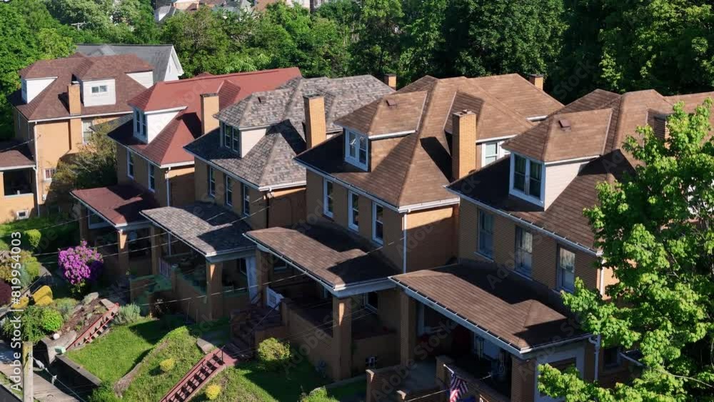 An aerial tilt up view from middle class homes on a hill to a small town's residential and business district in the distance below. Pittsburgh suburbs. An aerial tilt up view from middle class homes on a hill to a small town's residential and business district in the distance below. Pittsburgh suburbs.