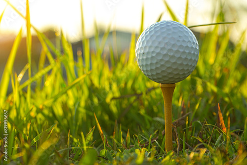 Golf ball is on tee at green lawn in a beautiful golf course with morning sunshine.