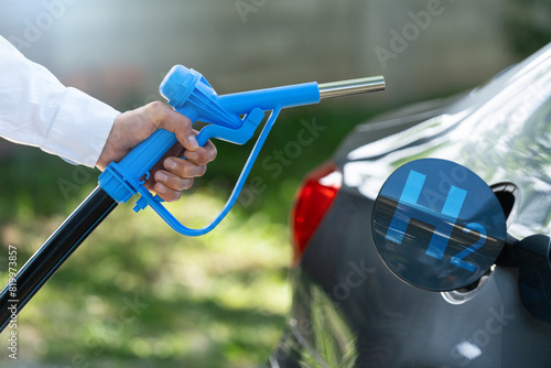 Man holds a hydrogen fueling nozzle. Refueling car with hydrogen fuel. Concept
