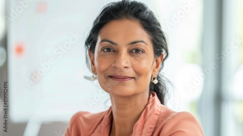 Smiling woman with dark hair wearing earrings and a pink blouse in an office setting with a window in the background. Free Download Smiling woman with dark hair wearing earrings and a pink blouse in an office setting with a window in the background. - GFXLoad