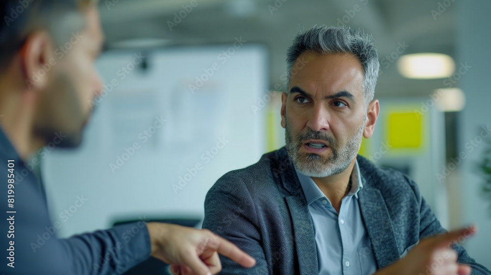 Fototapeta premium Two men engaged in a serious conversation in an office setting.