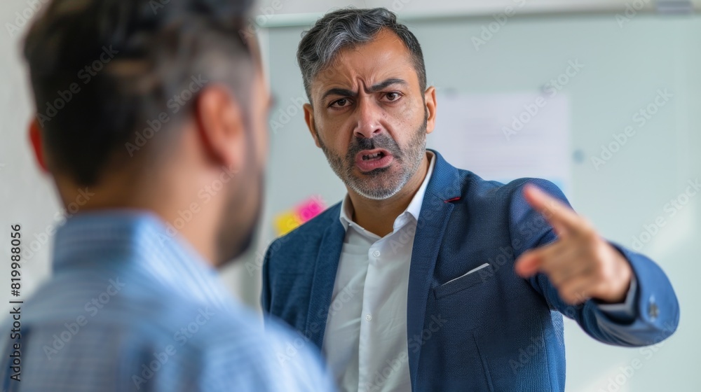 Man in blue suit jacket gesturing with pointed finger engaged in conversation with another man in blue shirt. Man in blue suit jacket gesturing with pointed finger engaged in conversation with another man in blue shirt.