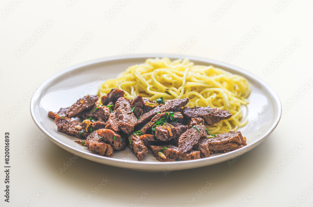 fake meat: fried seitan with noodles on a plate fake meat: fried seitan with noodles on a plate