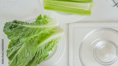 Leaves of fresh green lettuce, and fresh celery close-up on white background, flat lay. Celery lettuce salad recipe photo