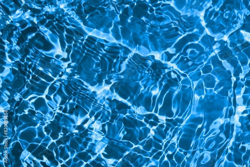 Blue and bright water in swimming pool with sun reflection
