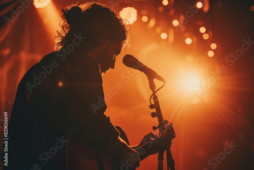 Silhouetted Musician Playing Guitar on Stage Under Warm Ambient Lights