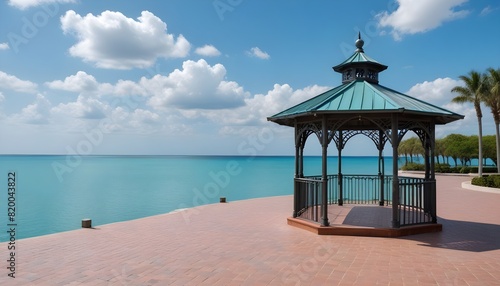 A gazebo on a paved plaza with turquoise blue water and a cloudy sky in the background