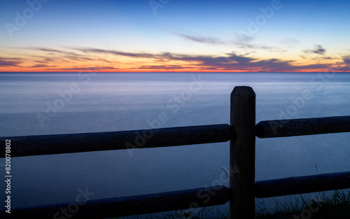 Fence in front of water at sunset