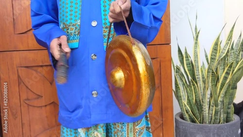 Cinematic shot. A young man of Betawi Tribal Musician playing the traditional instruments famously known as Gambang Kromong photo