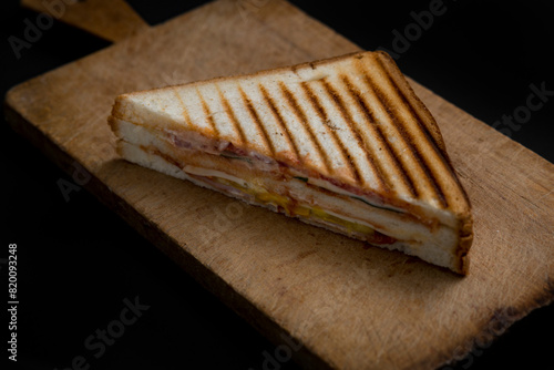 club sandwich on a wooden board on a dark background