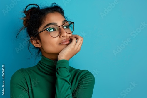 Mockup, Indian woman and thinking with decision, future and fantasy with girl against a blue studio background. Lady, imagination, chance, choice, astonishment, and eyeglasses
