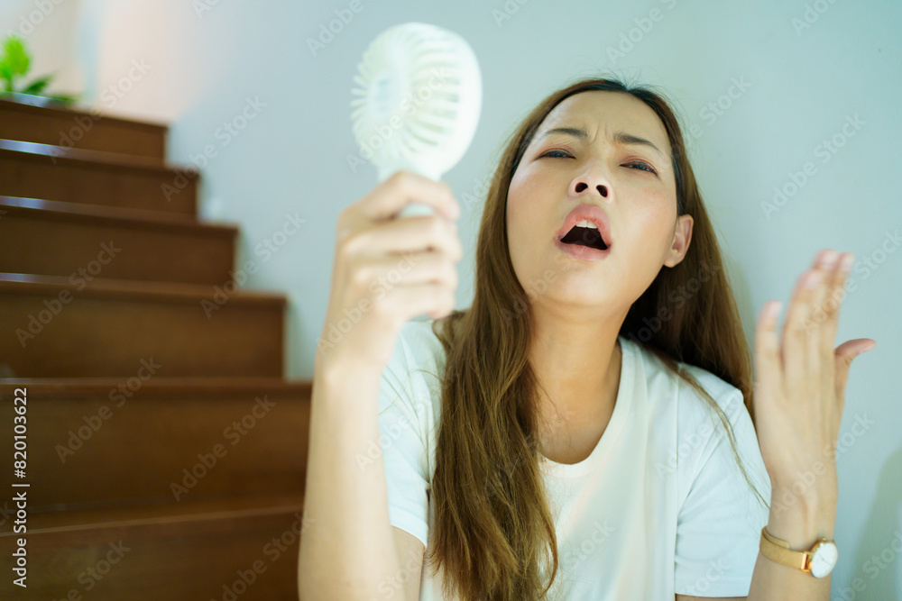 Asian woman using portable mini electric fan in the hotter day. Asian woman using portable mini electric fan in the hotter day.