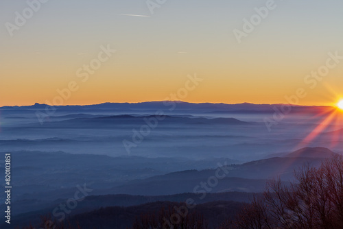 Sunrise Over Misty Mountain Ranges with Radiant Sunbeams © Rainer