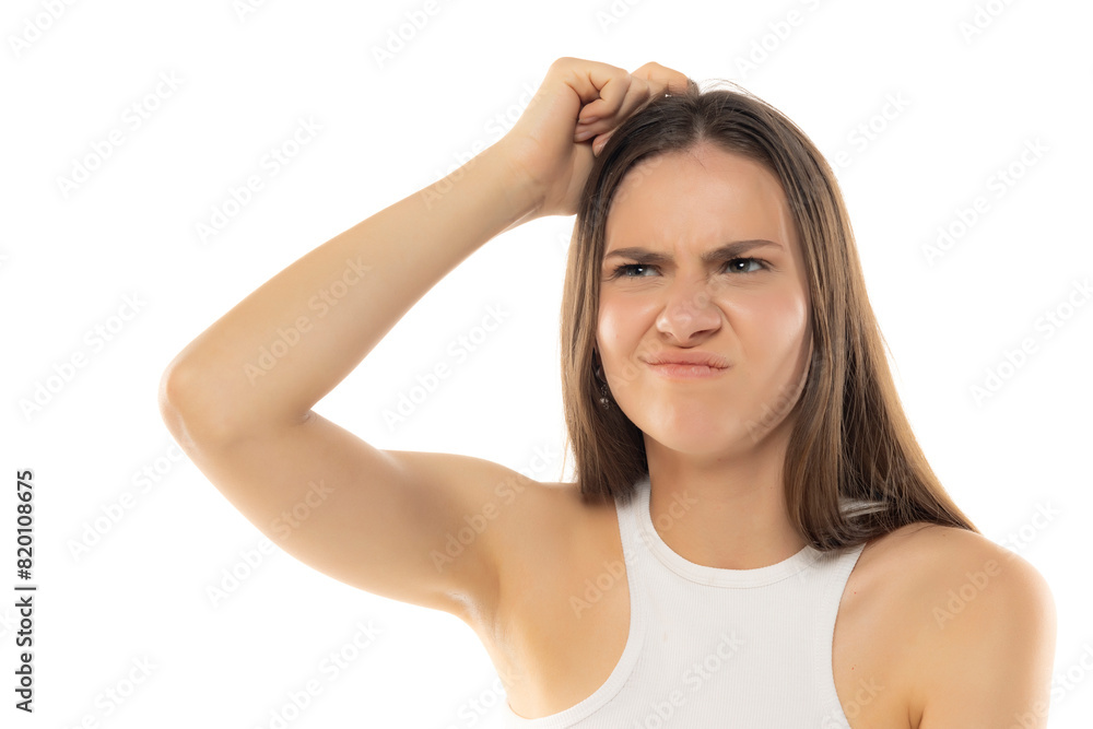 Portrait of a young teenage girl nervously thinking and scratching her head with her finger on a white background Portrait of a young teenage girl nervously thinking and scratching her head with her finger on a white background