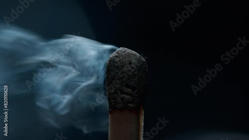 Blowing out a Match with Burnt Sulfur, Grey Smoke Rises in the Air on a Blue Background in Macro and Slow Motion photo