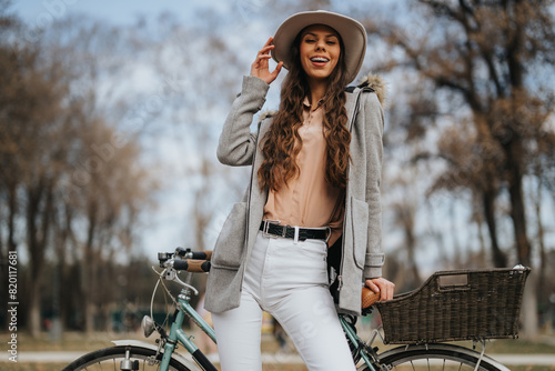 Stylish young woman with bicycle enjoying a sunny day in the park.