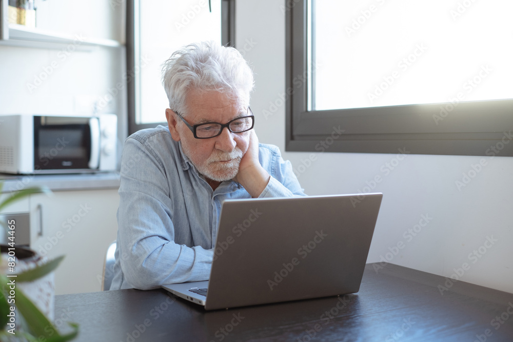 Video call concept. Serious senior caucasian businessman working online watching webinar podcast on laptop and learning education course conference calling sit at home desk, remote working Video call concept. Serious senior caucasian businessman working online watching webinar podcast on laptop and learning education course conference calling sit at home desk, remote working