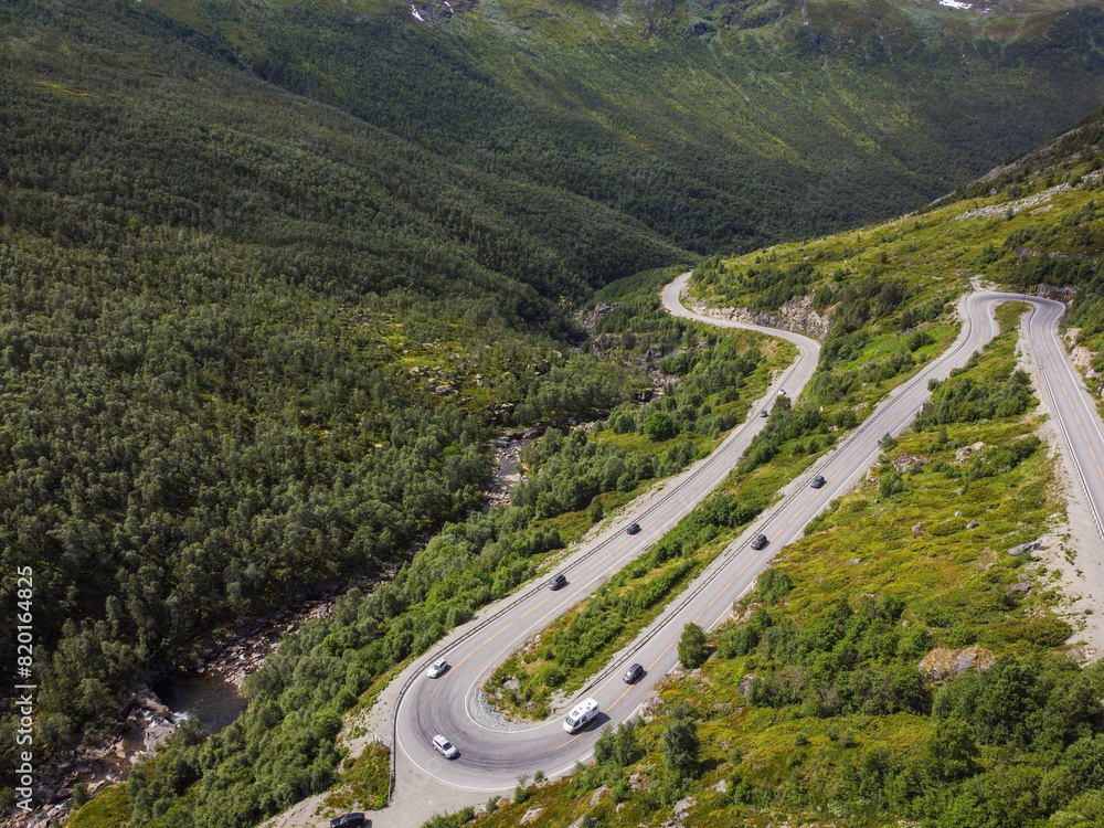 Borlaug, Norway. Cars Goes On Serpentine Mountain Road . Famous Norwegian Landmark And Popular Destination. Norwegian Hemsedalsvegen road In Summer Day. Borlaug, Norway. Cars Goes On Serpentine Mountain Road . Famous Norwegian Landmark And Popular Destination. Norwegian Hemsedalsvegen road In Summer Day.