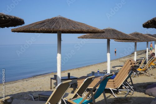 Sandy beach with sunbeds and straw umbrellas on the Olympic Riviera, Nei Pori, Pieria - Greece photo