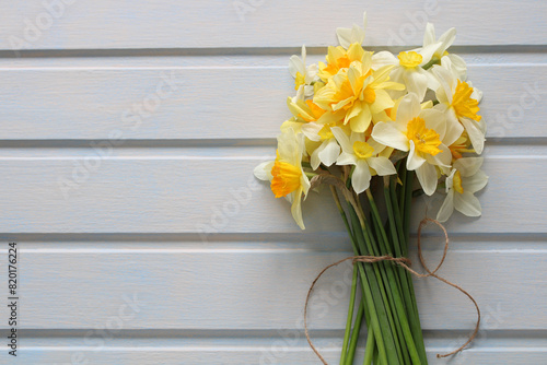 a bouquet of yellow daffodils on a plank white background, top view. kopi space. spring garden backdrop. photo