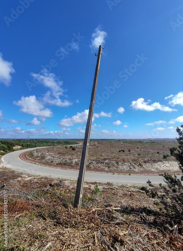 Barren Landscape with a Single Utility Pole and Winding Road under Clear Blue Sky. Central Portugal