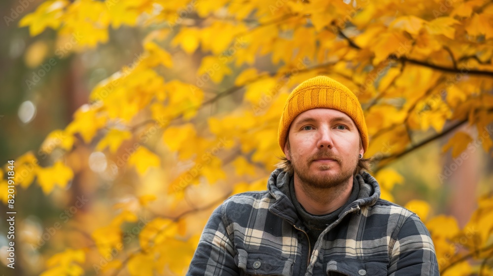 A man wearing a yellow hat standing in front of a tree in autumn A man wearing a yellow hat standing in front of a tree in autumn
