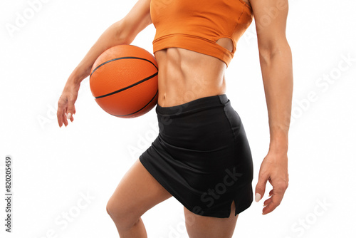 A beautiful slender girl athlete in shorts and in orange yop plays basketball. photo