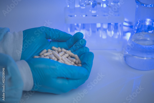 Doctor's hands holding vitamin capsules on chemical laboratory background, scientific laboratory research and development concept