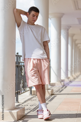 portrait of young man in white T-shirt, summer shorts and sneakers on street, fashionable man, urban style, theme of the LGBT community