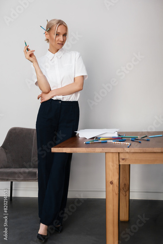 young beautiful blonde woman in white blouse and black trousers, the theme of copywriter or freelancer, studio