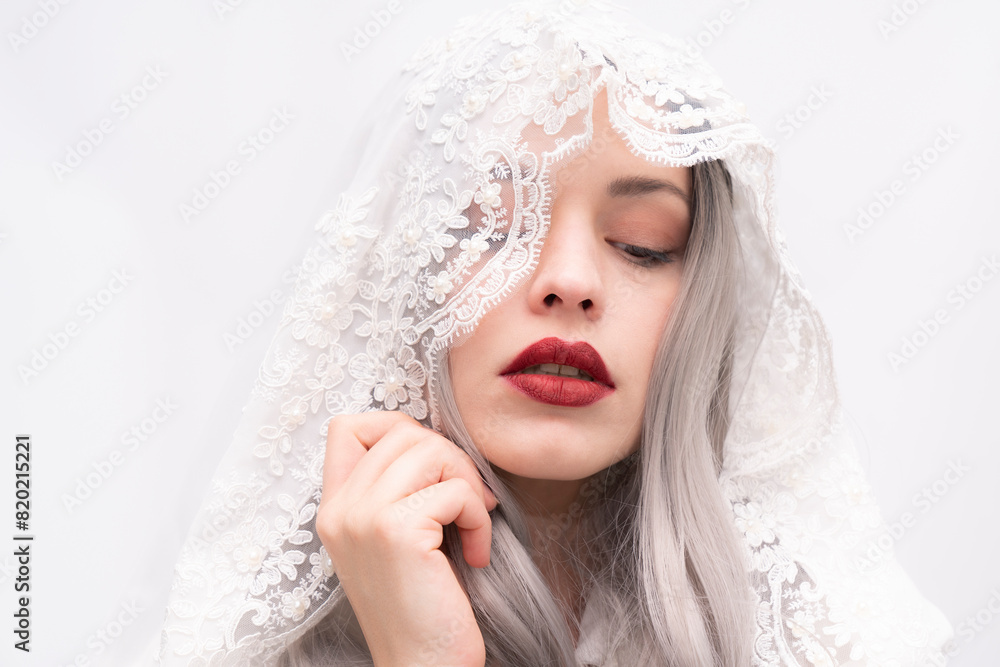 A woman with long gray hair and red lipstick is wearing a white veil A woman with long gray hair and red lipstick is wearing a white veil