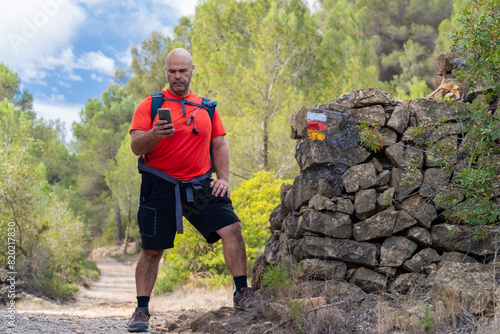 Male hiker using the phone outdoors, checking the way. photo