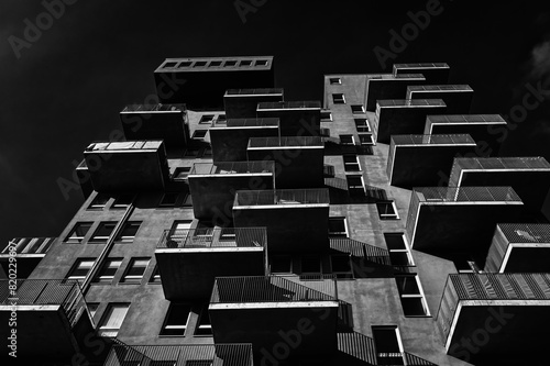 View from underneath of a residential building with balconies in black and white