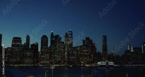 Static panorama of sleepless urban Manhattan cityscape in the dark evening gloom. Boat running on the East River