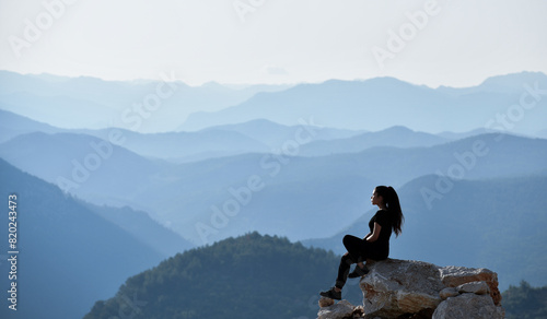 Foto Young lonely woman standing at a high viewpoint watching a majestic mountain range