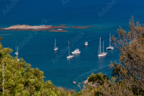 Sailboats at anchor in Corsica. Sailboats floating on the calm blue sea. Coastal summer landscape of Corsica  The Gulf of Sagone seen from Cargèse, Corsica, France photo